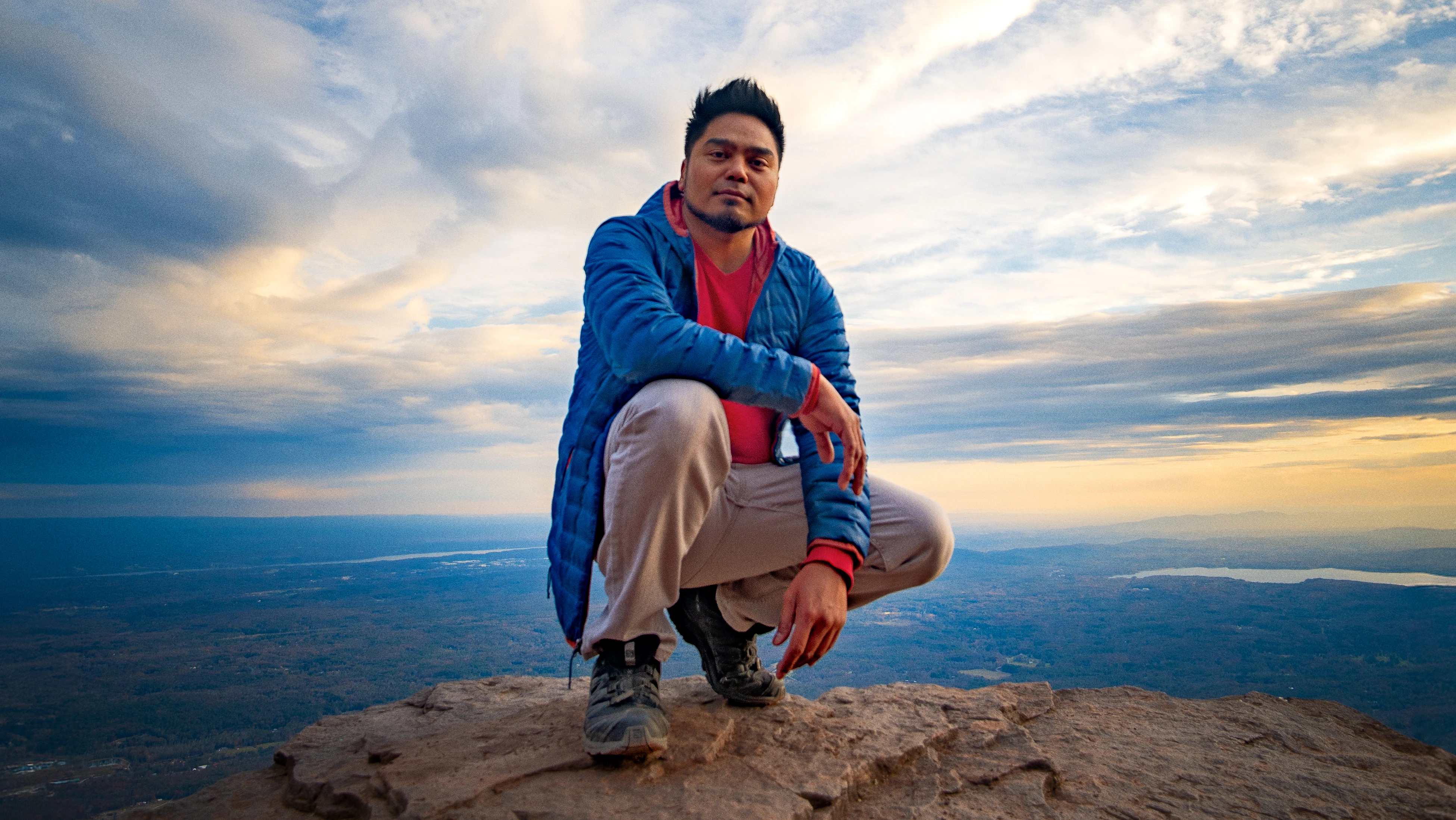 Jerome Mabini sitting on a mountain overlook at sunset